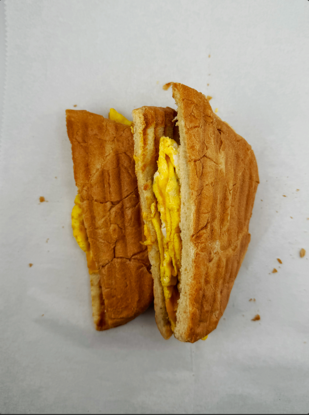 Pressed egg and cheese breakfast panini sliced in half on deli paper