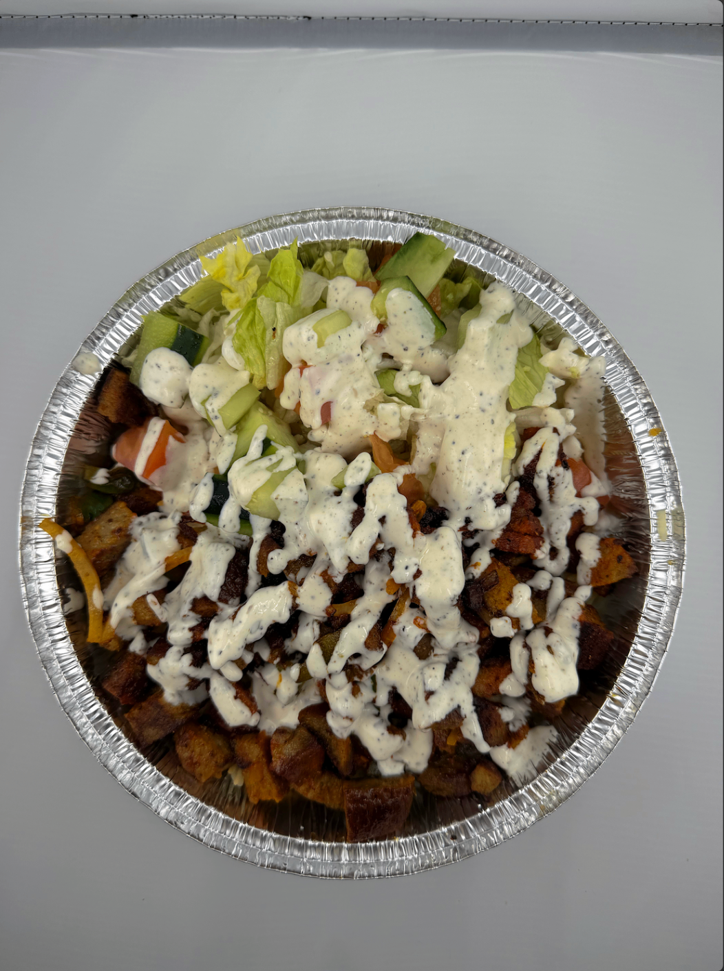 Loaded bowl with seasoned potatoes, fresh salad, and creamy ranch drizzle