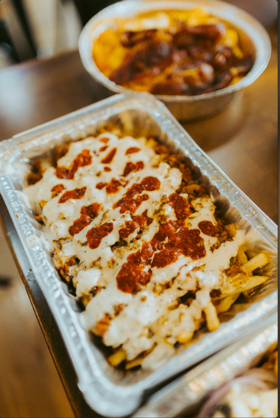 Loaded fries tray covered with white sauce and red sauce