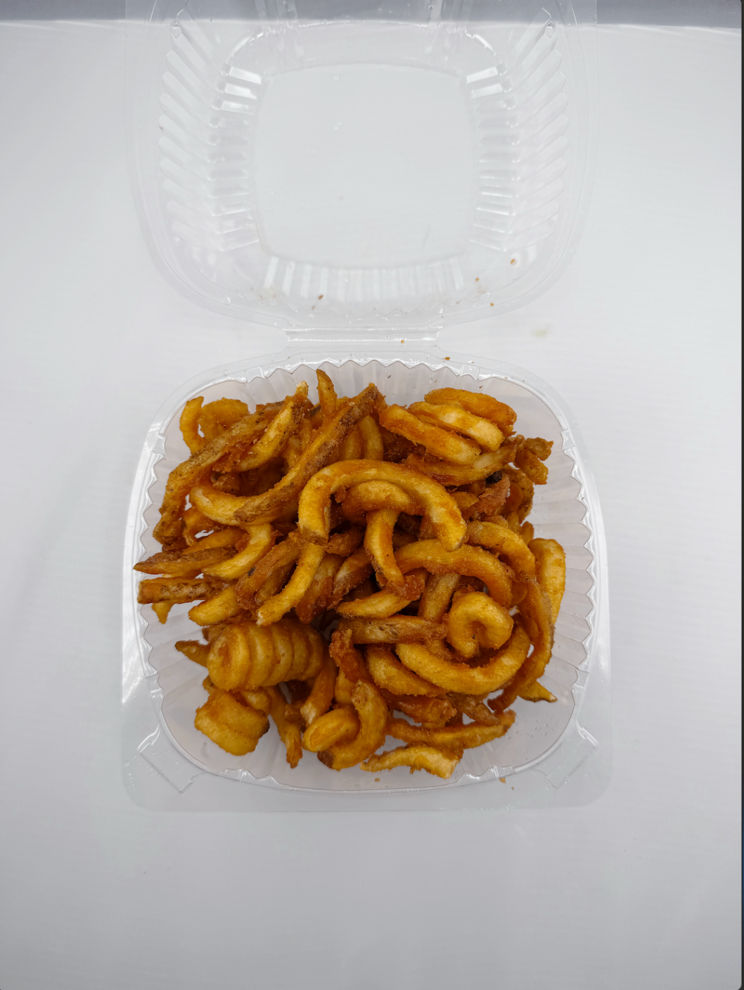 Box of seasoned curly fries served hot in a takeout container