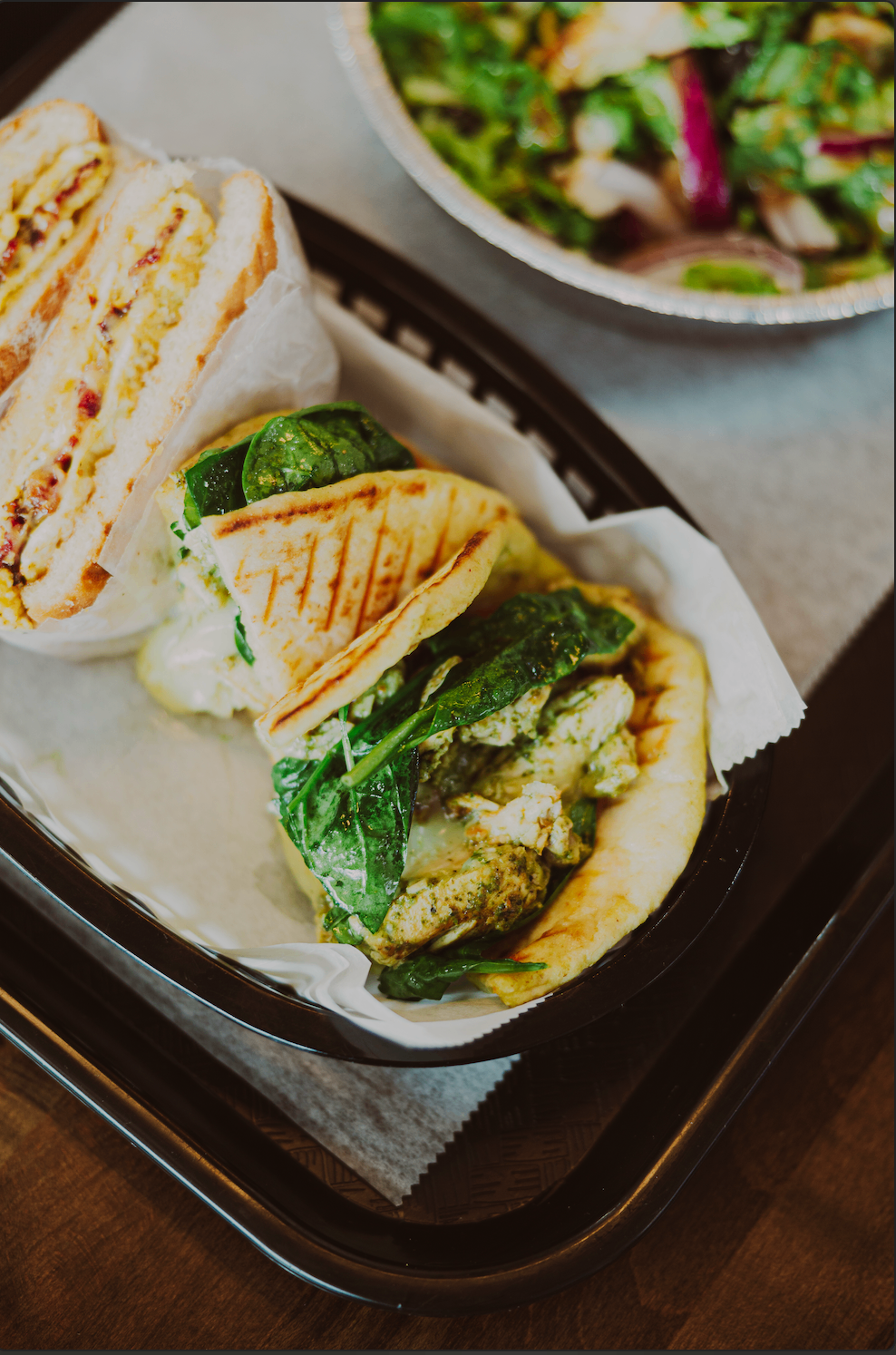 Close-up tray of pesto chicken wrap and fresh salad