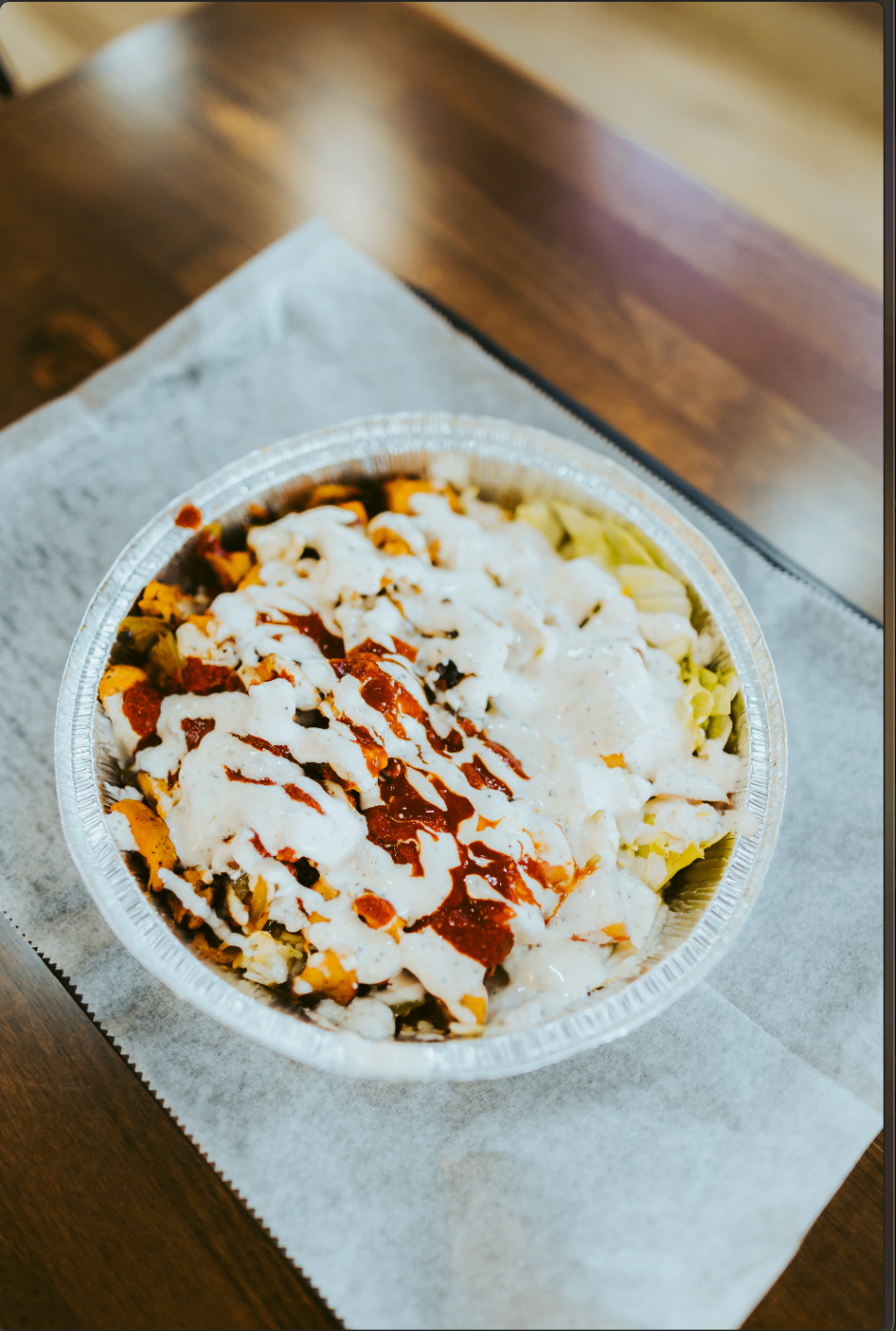 Halal platter topped with white sauce and red sauce